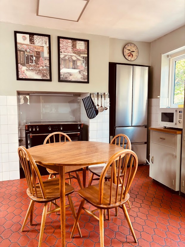 The kitchen at Blue Waters with a round wooden table, range cooker and terracotta tiled floor