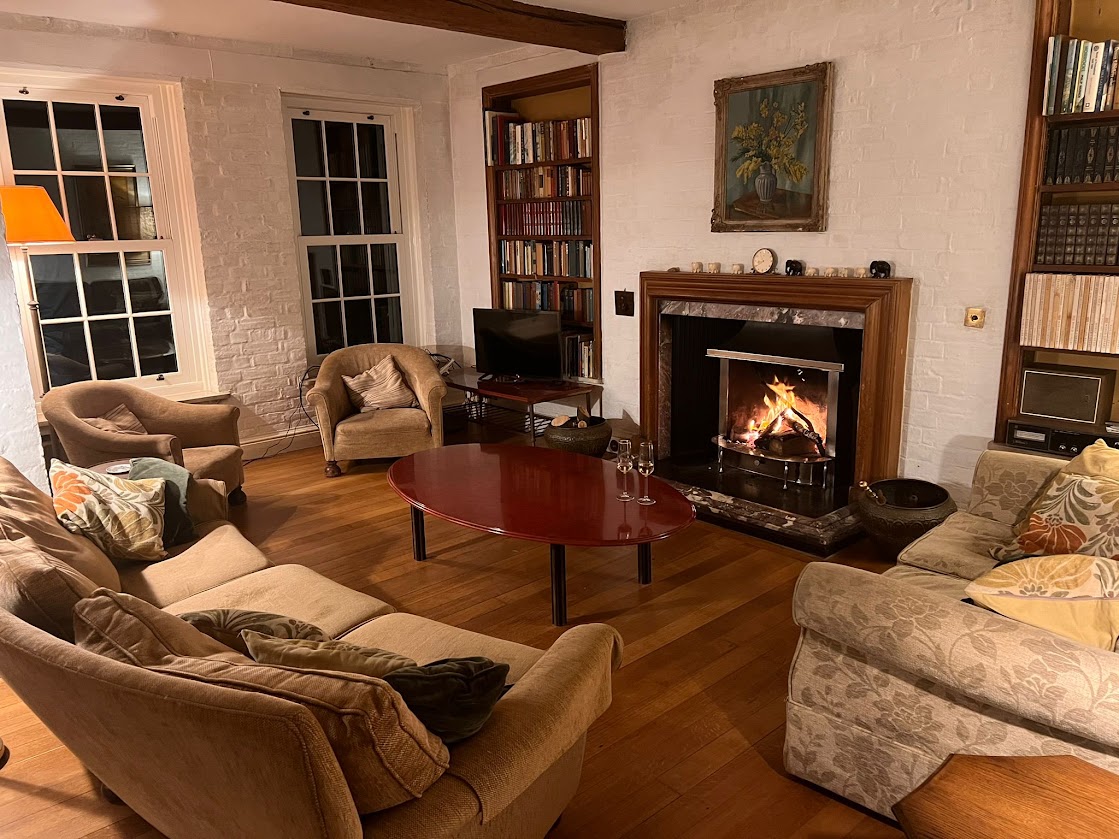 The sitting room at Blue Waters at night with the open fire lit, lamps glowing and sofas gathered round
