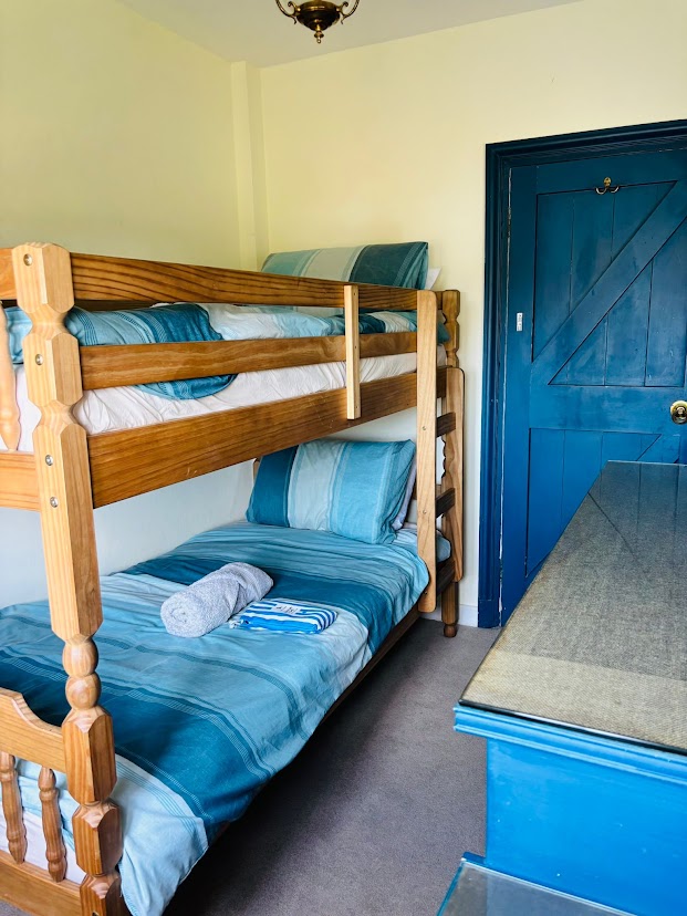 The children's bunk room at Blue Waters with wooden bunk beds, blue striped bedding and a blue painted door