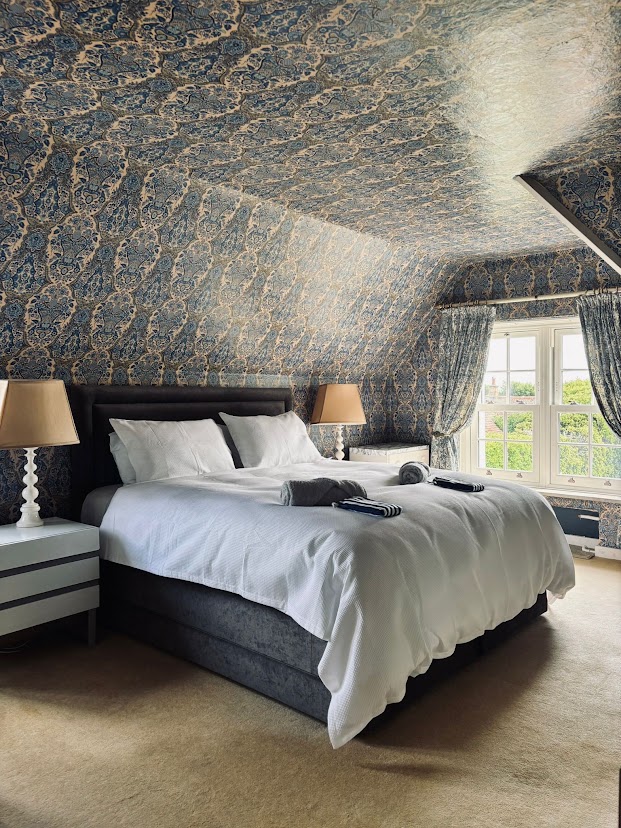 Bedroom 3 at Blue Waters with twin single beds, patterned blue wallpaper and bedside lamps by the window