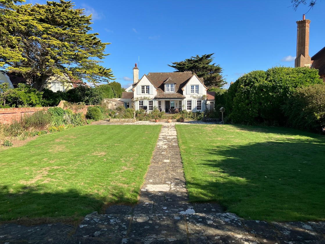 Blue Waters seen from the end of the garden, with a stone path across the lawn leading to the house