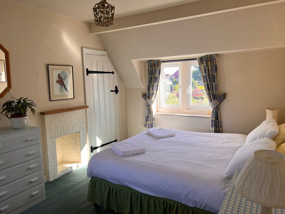 Bedroom 5 at Blue Waters with a double bed, a whitewashed brick fireplace and checked curtains