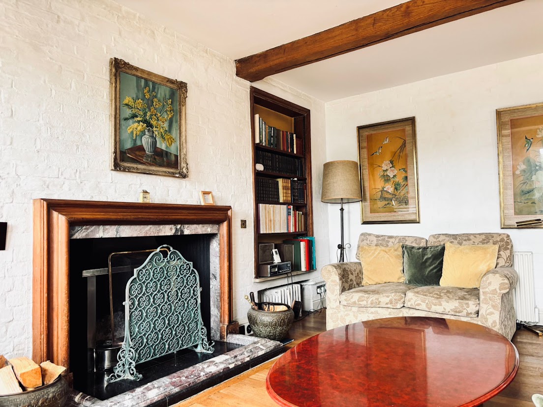 The sitting room at Blue Waters with an open fireplace, built-in bookshelves and a comfortable sofa