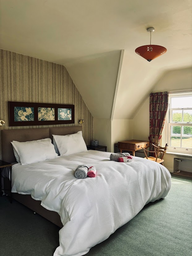 A double bedroom at Blue Waters under the eaves with striped wallpaper and white linen